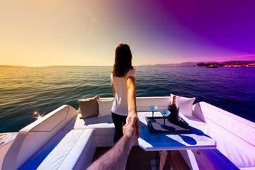 woman holding man's hand on luxury yacht