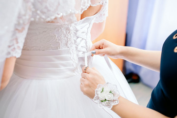 Wedding dress close-up hands knotted corset bride.