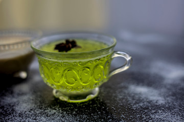 Rice flour and rice grain on wooden surface along with some green tea in a transparent glass cup and a star anise in it.Face mask for the treatment for smoother skin.
