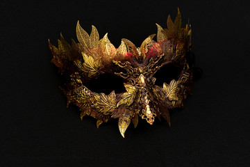 Venetian mask in gold and red with metallic pieces in the form of leaves. original and unique design, handmade crafts