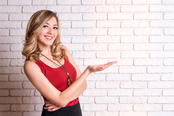 Happy young woman showing copyspace pointing. Blond young female pointing fingers away. Copy space for your text or advertising content.