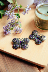 Butterfly-shaped female adornment on wooden background next to flowers