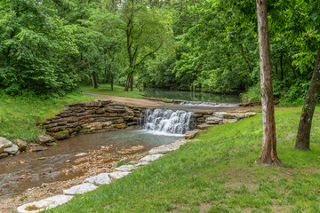 Stream through canyon park with cascading water over stone walkway