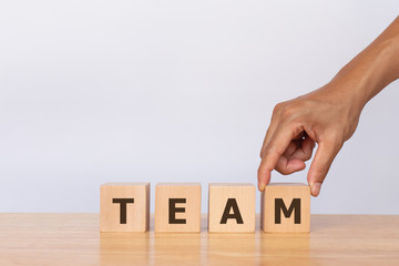 Hand putting house model on wooden cubes with alphabet TEAM. Concept of human resources management and recruitment business