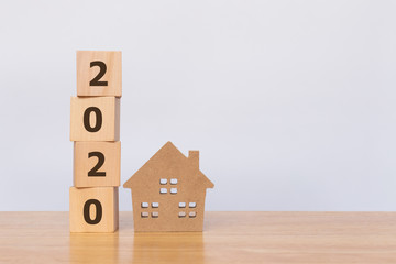 House model and wooden cubes with 2020 on wooden table. Investment concept
