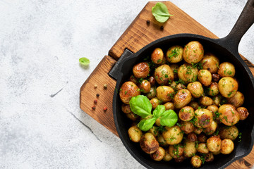 Fried, young potatoes with basil in a pan. View from above.