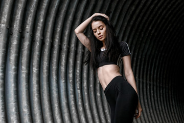 Sports woman posing in fashion sportswear on tunnel urban gray background. Fitness model working...