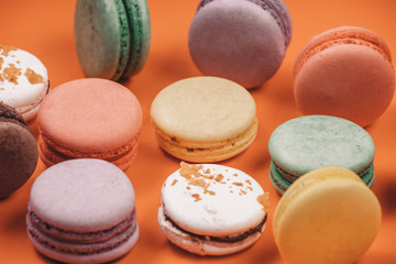 Sweet delicious colorful set of macaron on coral or orange background. French traditional dessert