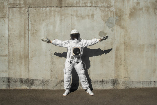 Futuristic astronaut in a helmet against gray walls. Fantastic Cosmic Costume.