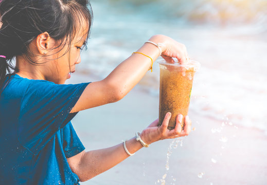 Children Is Holding Plastic Bottle That He Found On The Beach For Enviromental Clean Up Concept