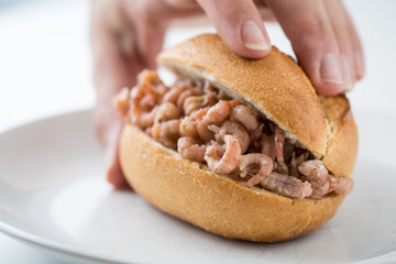 Frau isst Nordseekrabben Brötchen als Fischbrötchen als schneller regionaler Imbiss