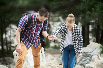 Romantic couple climbing the rocks while hiking