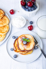 Cottage cheese pancakes (syrniki). Homemade cheesecakes from cottage cheese with sour cream, berries and milk. Traditional Russian dish. Close-up.