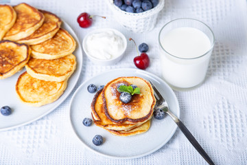 Cottage cheese pancakes (syrniki). Homemade cheesecakes from cottage cheese with sour cream, berries and milk. Traditional Russian dish. Close-up.