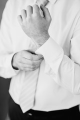 The man put on his shirt and straightens cufflinks. The groom fasten cufflinks on the cuffs of the shirt. The businessman fasten cufflinks on the cuffs of the shirt. Concept successful businessman.