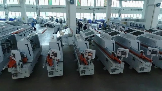 A large factory for the production of automated machine tools. Manufactured woodworking machines stand in a row in stock. Warehouse of woodworking machines