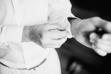 The man put on his shirt and straightens cufflinks. The groom fasten cufflinks on the cuffs of the shirt. The businessman fasten cufflinks on the cuffs of the shirt. Concept successful businessman.