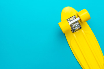 minimalist flat lay photo of yellow plastic mini cruiser board on blue background. top view of...