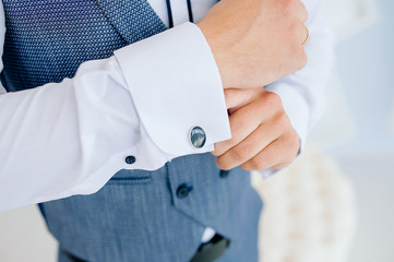 The man put on his shirt and straightens cufflinks. The groom fasten cufflinks on the cuffs of the shirt. The businessman fasten cufflinks on the cuffs of the shirt. Concept successful businessman.