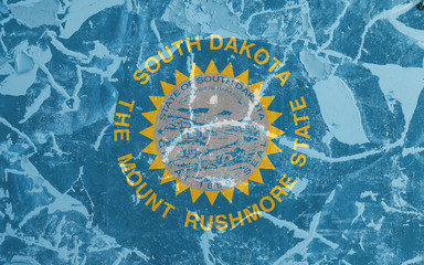 The national flag of the US state South Dakota in against a gray wall with cracks and faults on the day of independence in blue and yellow. Political and religious disputes, customs and delivery.