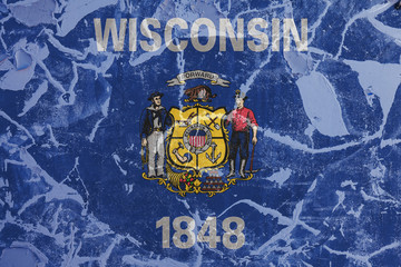 The national flag of the US state Wisconsin in against a gray wall with cracks and faults on the day of independence in color of blue and yellow. Political and religious disputes, customs and delivery
