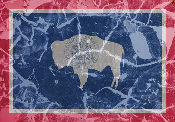 The national flag of the US state Wyoming in against a gray wall with cracks and faults on the day of independence in colors of blue red. Political and religious disputes, customs and delivery.