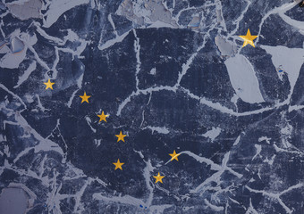 The national flag of the US state Alaska in against a gray wall with cracks and faults on the day of independence in colors of blue ground and yellow stars. Political and dispute, customs and delivery