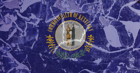 The national flag of the US state Kentucky in against a gray wall with cracks and faults on the day of independence in colors of blue and yellow. Political and religious disputes, customs and delivery