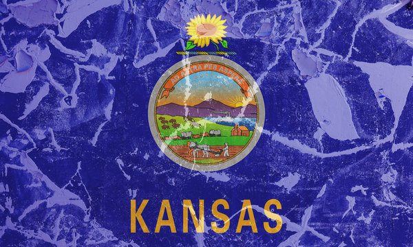 The national flag of the US state Kansas in against a gray wall with cracks and faults on the day of independence in colors of blue and yellow. Political and religious disputes, customs and delivery.