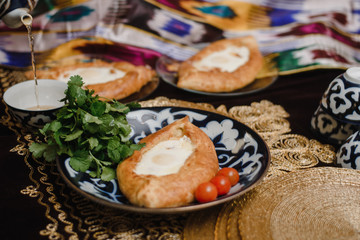Adjara khachapuri on the eastern table. egg in hot bread on oriental plates is in a restaurant.
