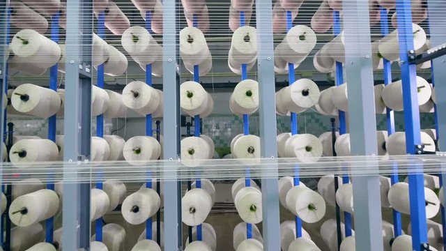 Tailoring loom with winding threads. Industrial textile factory.