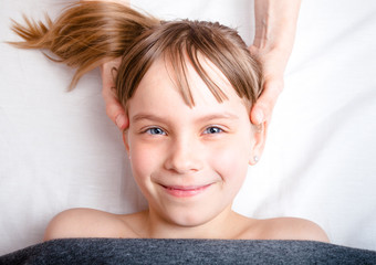 Girl receiving osteopathic treatment of her head in pediatric clinic
