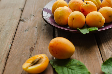 Delicious ripe apricots in a wooden bowl on the table close-up.