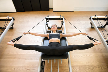 Adult using pilates machine to stretch legs