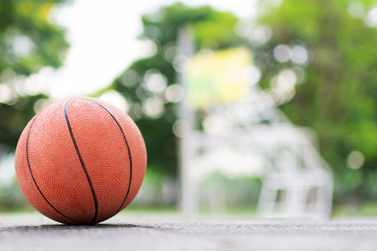 Orange ball put on the cement floor for ready to play in basketball court at the park. - Powered by Adobe