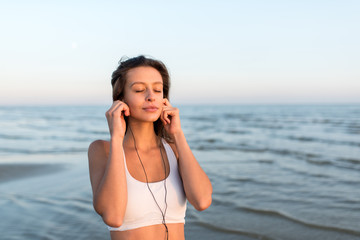 Sports fitness exercising woman on the beach listening to music