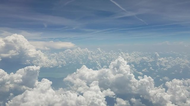 Aerial background with a real time flight above puffy clouds, as seen from an airplane.