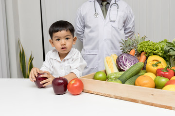 Fototapeta premium A boy and doctor happy to have healthy food. Kid learning about nutrition with doctor to choose eating fresh fruits and vegetables.