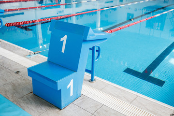 Starting block, number 1, swimming pool with an empty race track. Sport swimming