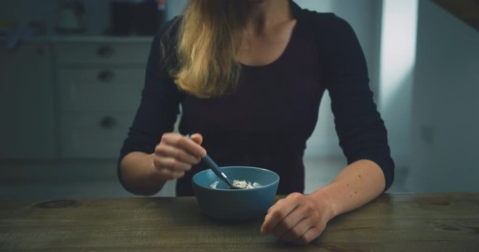 Young woman eating breakfast in her kitchen