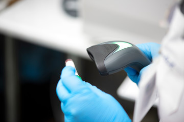 Bar code scanner and test tube over monitor of complete blood count analyzer in background.