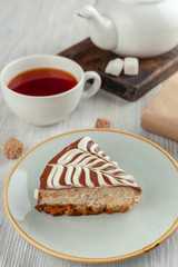 A piece of homemade moist sponge cake with coffee and grapefruit frosting and a cup of black tea