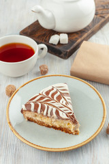 A piece of homemade moist sponge cake with coffee and grapefruit frosting and a cup of black tea