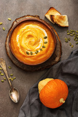 Autumn soup. Homemade cream pumpkin soup with seeds and toast on a dark rustic background....