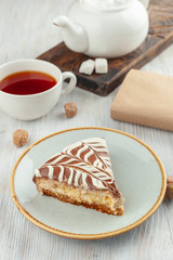 A piece of homemade moist sponge cake with coffee and grapefruit frosting and a cup of black tea