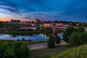 panorama view on evening in old town on the bank of wide river with evening fluffy curly rolling cirrostratus clouds and blue violet red sunset sky as background