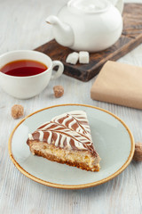 A piece of homemade moist sponge cake with coffee and grapefruit frosting and a cup of black tea