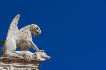 Griffon symbol of the city of Perugia in Umbria. Ancient 14th century medieval marble statue of the mythical beast against blue sky (with copy space)