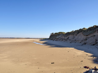 Breiter Sandstrand in der Normandie unter blauem Himmel