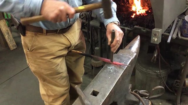 blacksmith strikes hammer punches hot metal anvil